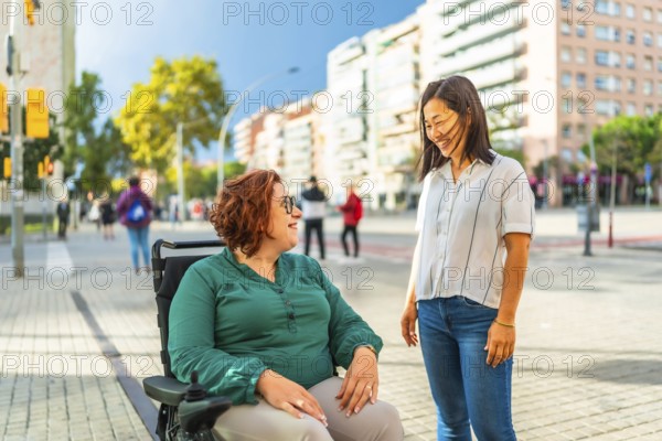Woman with disabilities and asian caregiver talking relaxed in the city