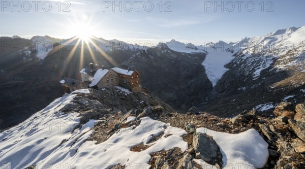 Mountain panorama and glacier, mountain hut Ramolhaus in autumn with snow, view of Gurgler Ferner with summit Hochwilde and Falschungsspitze, at sunrise with sun star, Ötztal Alps, Tyrol, Austria, Europe