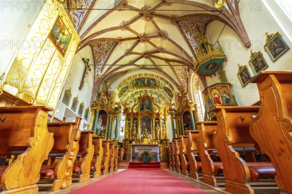 Interior of the church of st. Magdalena in val di funes, showing frescoes, pews and red carpet, in the dolomites, italy