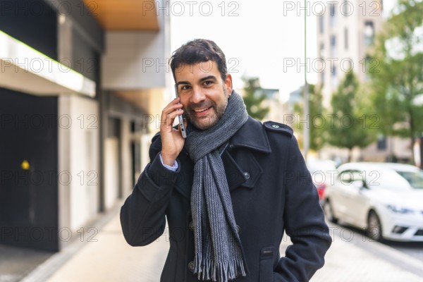 Happy elegant man talking to the mobile phone walking in the city