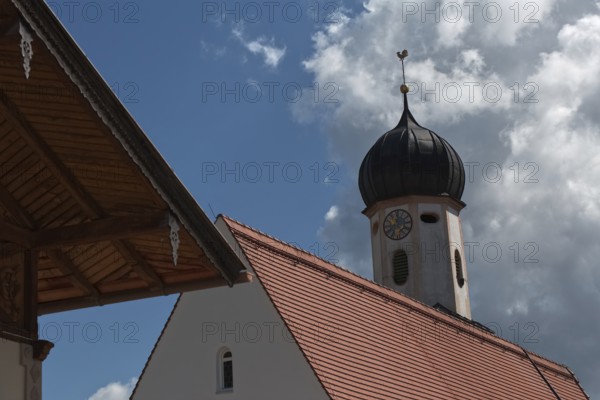 A baroque church tower and part of a roof in front of a blue sky with clouds, Wallgau, Bavaria, Germany, Europe