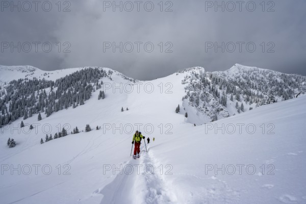 Ski tourers on the ascent to Raukopf, mountain landscape in the snow, mountain peaks Tanzeck and Aiplspitz, dramatic clouds, Mangfallgebrige, Bavaria, Germany, Europe