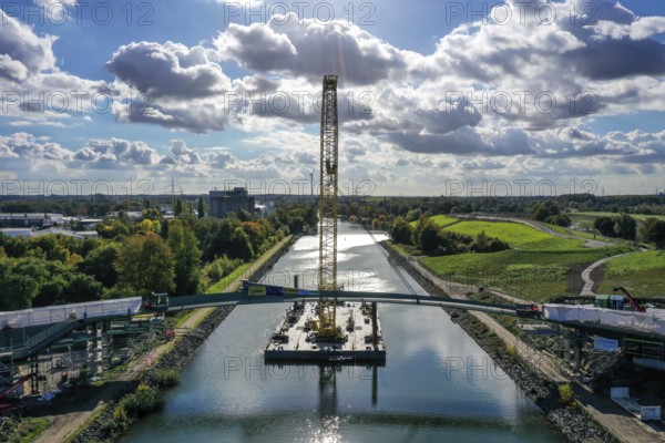 Recklinghausen, Castrop-Rauxel, North Rhine-Westphalia, Germany, New construction of a bridge -jump over the Emscher-, a floating crane on the Rhine-Herne Canal floating in the centre section of a foot and cycle bridge over the Emscher and the Rhine-Herne Canal. EMSCHERLAND construction project, a 37-hectare water and nature adventure park at the water crossroads of the Rhine-Herne Canal and the renaturalised Emscher on the border between Recklinghausen and Castrop-Rauxel. EMSCHERLAND will also be a garden of the future for the International Garden Exhibition 2027. Before the renaturalisation, the Emscher river system was an open, above-ground wastewater canal, mixed water canal with surface water and wastewater, Europe