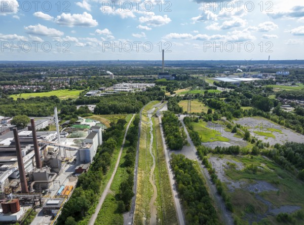 Bottrop, North Rhine-Westphalia, Germany, Renaturalised Boye, the tributary of the Emscher, was transformed into a near-natural watercourse, flood protection through newly designed flooding areas, the Boye is now free of wastewater after the construction of a parallel sewer, is part of the Emscher river system and thus part of the Emscher conversion, was previously an open, above-ground wastewater channel, mixed water channel with surface water and wastewater. Left Industrial area with chimneys on Essen territory, Europe