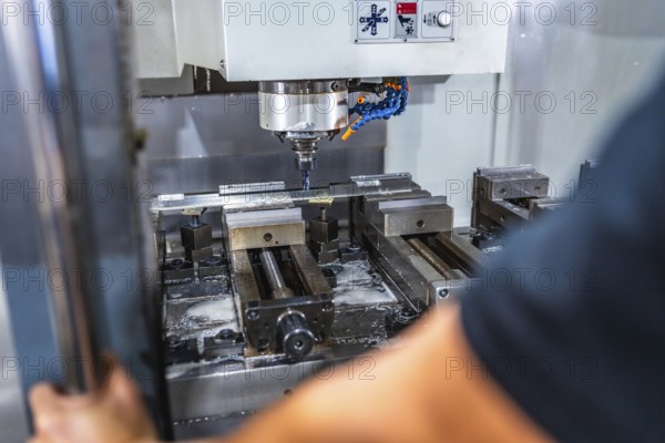 Rear view close-up of an unrecognizable man working with milling machine in cnc factory