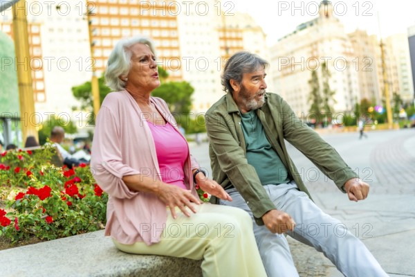 Senior couple of tourists resting on bench with tired expression in the city
