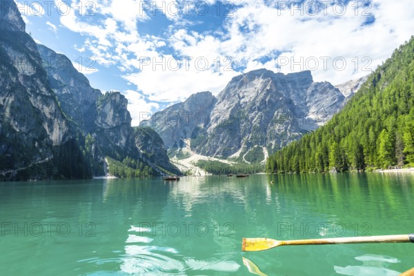Wooden oar rowing on the turquoise water of lake braies, surrounded by the stunning peaks of the dolomites, italy, on a sunny summer day