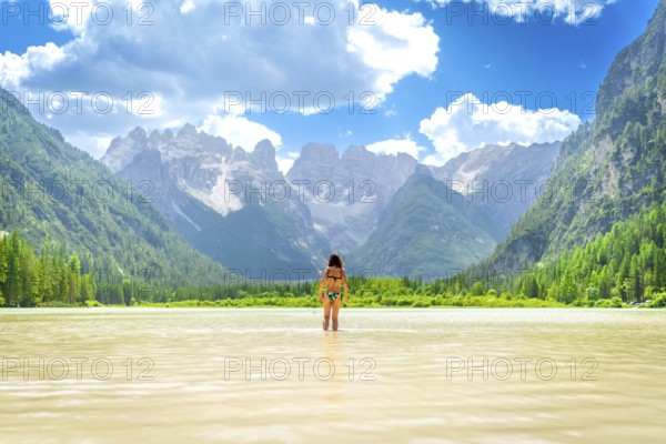 Woman wearing bikini enjoying a refreshing swim in the crystal clear waters of lago di landro, surrounded by the breathtaking peaks of the dolomites