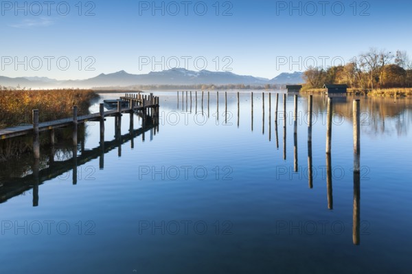 Footbridge and wooden post at the Chiemsee in autumn in the morning light, behind the Chiemgau Alps, Chiemgau, Bavaria, Germany, Europe