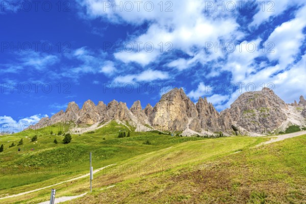 Green meadows and imposing peaks of the dolomites illuminated by the summer sun, creating a picturesque landscape in the italian alps