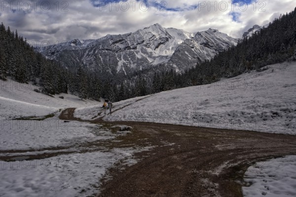 Picturesque view of snow-covered mountains on a path in front of dramatic clouds, Krün, Bavaria, Germany, Europe