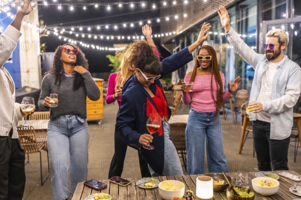 Caucasian woman drinking beer and dancing with multi-ethnic friends at outdoor night party