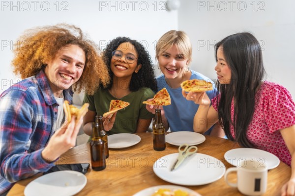 Four young, cheerful friends of diverse backgrounds enjoying pizza and beer together at home, celebrating friendship and good times