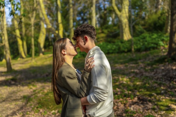Young couple embracing and sharing a tender moment in a beautiful forest, surrounded by trees and sunlight