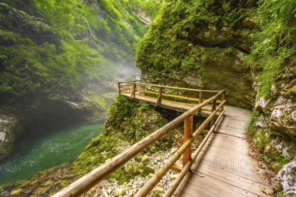 Breathtaking view of wooden walkway over stunning emerald river flowing through vintgar gorge near bled, slovenia, a picturesque natural wonder