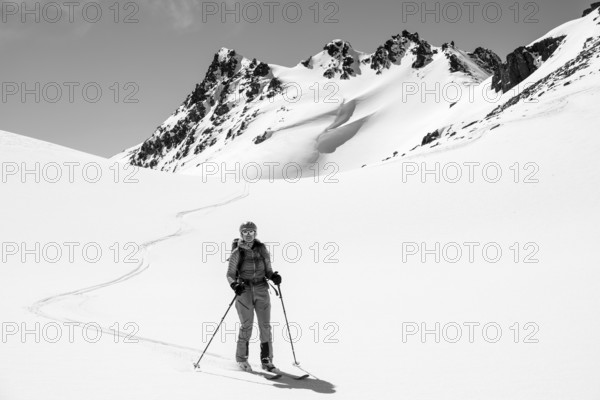 Ski tourer on the descent, minimalist winter landscape, white snow and dark mountains on the Scalettahorn, Graubünden, Switzerland, Europe