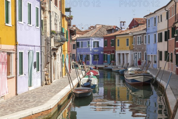 Colourful houses along a quiet canal with parked boats on the island of Burano, Venice, Italy, Europe