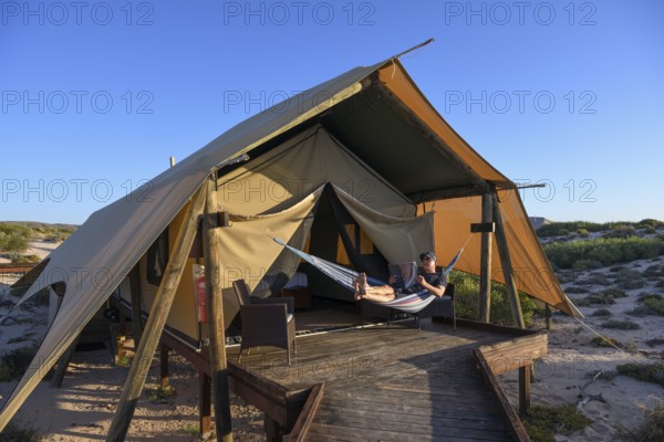 Tourist in a hammock, luxury camp Sal Salis, Cape Range National Park, Ningaloo Reef, near Exmouth, Western Australia, Australia, Oceania
