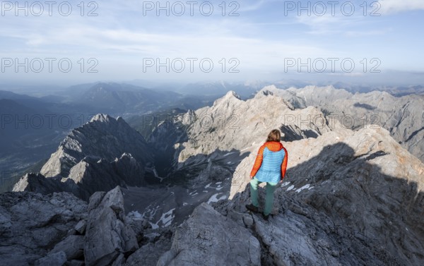 Mountaineer on a narrow rocky steep mountain ridge, view into the Höllental and to the Alpspitze from the Jubiläumsgrat, in the evening light Zugspitze, Wetterstein range, Bavaria, Germany, Europe