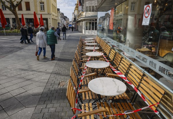 Krefeld, North Rhine-Westphalia, Germany - Krefeld city centre in times of the corona crisis during the second lockdown, a café restaurant has cordoned off the outdoor seating with flutter tape, most shops are closed, only a few passers-by are walking on Hochstraße, the main shopping street