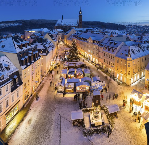 The snow-covered Christmas market with St Wolfgang's church seen from the town hall tower, Schneeberg in the Ore Mountains, Saxony, Germany, Europe