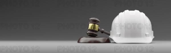 White hard hat and gavel on a gradated background banner with room for text or graphics