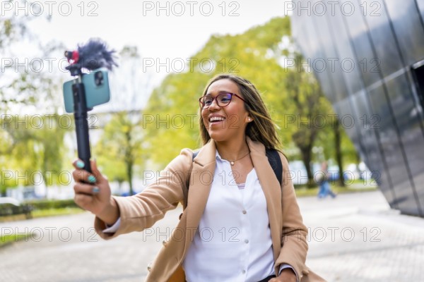 Happy latin woman influencer vlogging while walking along the city