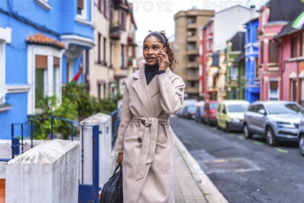 Elegant and beauty african american businesswoman wearing trench coat talking to the mobile phone in the city
