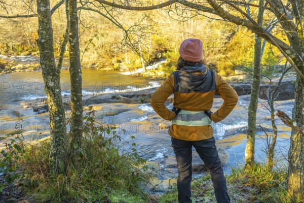 Female hiker enjoying the view of the baias river in the gorbeia natural park on a sunny autumn day