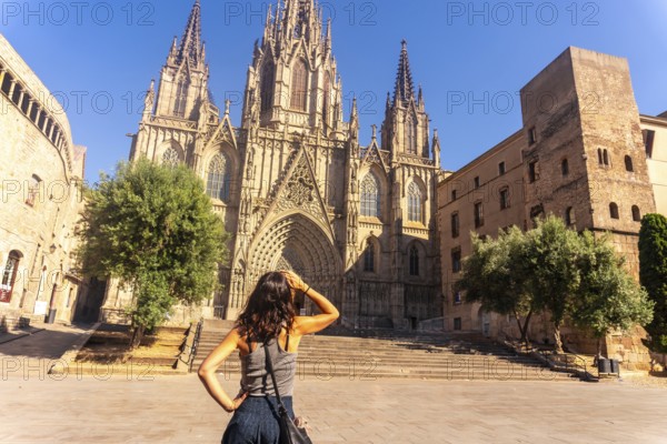 Young woman shielding her eyes from the sun while contemplating the majestic barcelona cathedral in the gothic quarter during a summer vacation