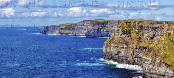 Sweeping views of steep cliffs and azure sea under a cloudy sky, Cliffs of Moher