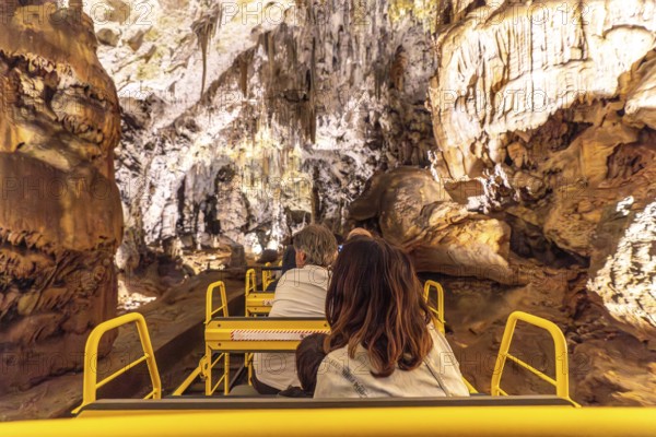 Tourists enjoying a train ride inside the magnificent postojna cave, a famous natural wonder in slovenia, during their family vacation