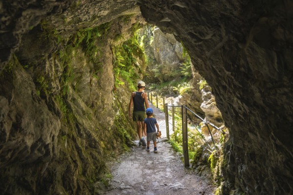 Mother and son walking through a natural rock tunnel, enjoying the stunning views of tolmin gorge in slovenia