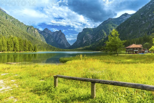Stunning landscape showing the reflections of the dolomites mountains on the calm waters of lake dobbiaco during a beautiful summer day