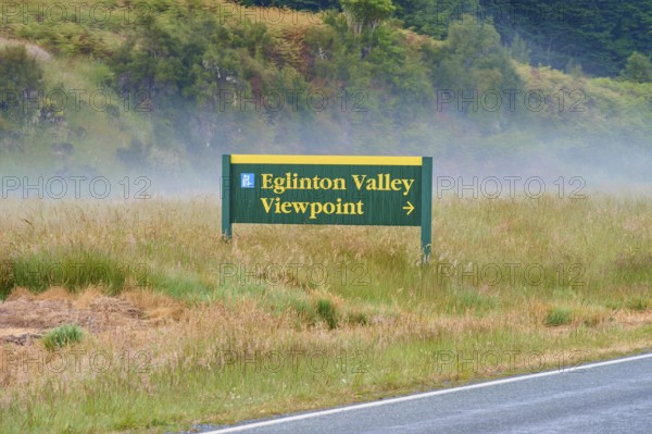 Sign showing the way to Eglinton Valley viewpoint, surrounded by misty pasture, summer, Milford Sound, Te Anau, Fiordland National Park, South Island, New Zealand, Oceania