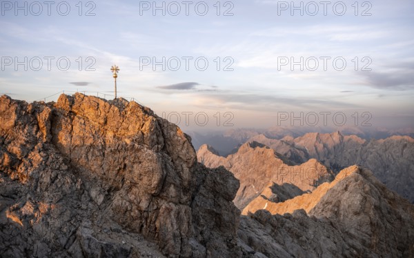 Summit of the Zugspitze with golden summit cross, alpenglow at sunset, Northern Limestone Alps, Wetterstein Mountains, Bavaria, Germany, Europe