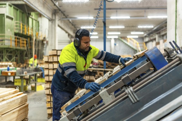 Male caucasian worker of a recycling plant repairing a pallet for reuse in the workshop