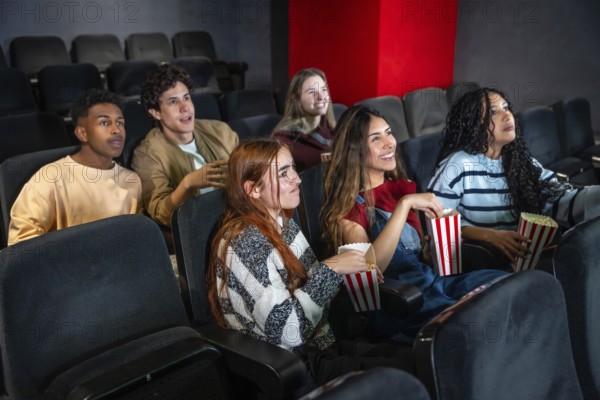 Group of diverse friends enjoying a film at the movie theater, eating popcorn and having fun together