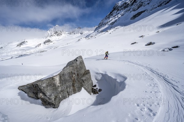 Ski tourer ascending through a picturesque snow-covered mountain landscape with views of mountain peaks, ascent to the summit of Kesch Pitschen, Bündner Haute Route ski tour, Albula Alps, Rhaetian Alps, Grisons, Eastern Switzerland, Switzerland, Europe
