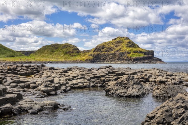 Broad coastal landscape with grassy hills and rocks in the sea, Giant Causeway