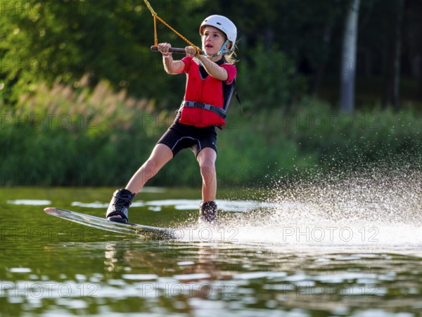 Boy or girl with wakeboard in the lake, water sports, water skiing in the wake park