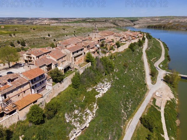 A village on a river with a raised road and green surroundings as well as densely built-up houses, aerial view, Maderuelo, Río Riaza, River Riaza, Embalse de Linares del Arroyo dam, Segovia, Castile and León, Leon, Spain, Europe