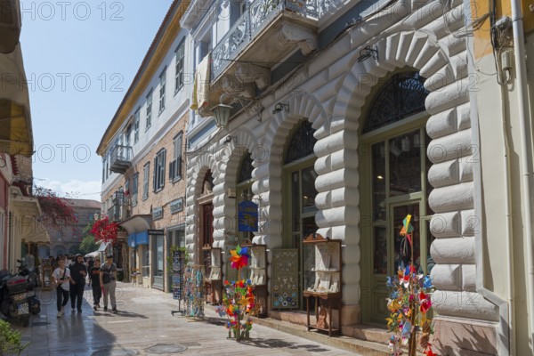 Lively shopping street with historic buildings, shop windows and colourful windmills under a blue sky, Nafplio, Nauplia, Nauplion, Nafplion, Argolis, Peloponnese, Greece, Europe