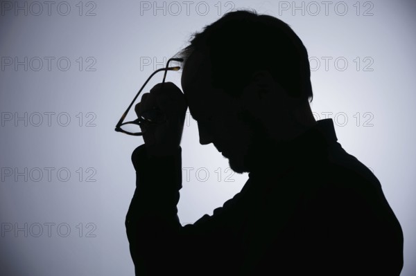 Symbolic photo on the subject of overload. Silhouette of a man rubbing his aching head. Berlin, 22/08/2024
