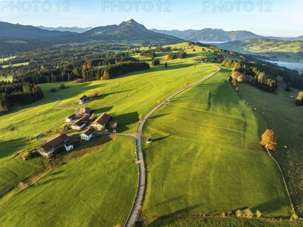 Mountain range near village Wertach, view to mt. Gruenten, sunrise, fog in valley, traditional farm, autumn colors, aerial view, Allgaeu, Bavaria, Germany, Europe