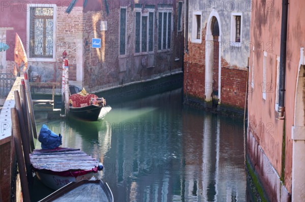 View from a gondola on a waterway in Venice going through the houses on a quiet and sunny morning in winter, Italy, Europe