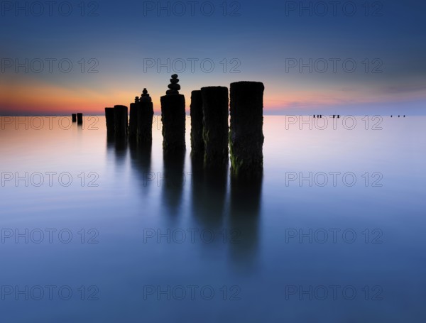 Stone pyramids on old groynes with algae in the water on the beach of the Baltic Sea, long exposure at sunset, Wustrow, Fischland-Darß-Zingst peninsula, Mecklenburg-Vorpommern, Germany, Europe