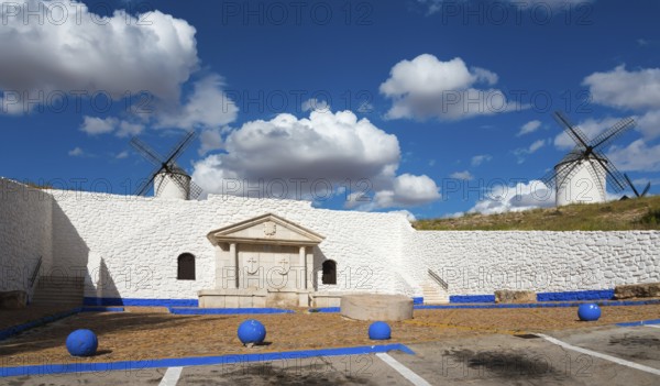 Two windmills and a stone wall against a blue sky full of clouds, Fuente del Caño, open-air museum, Campo de Criptana, Ciudad Real province, Castilla-La Mancha, Don Quixote Route, Spain, Europe