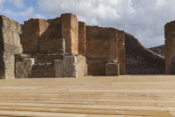 Wood plank decking and remnants of an old terracotta brick and stone wall structure at the ancient ruins of Pompeii, Campania region, Italy, Europe