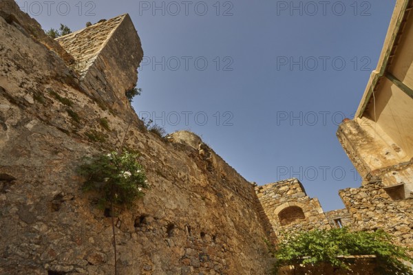 An old stone wall with vegetation and ruins under a bright blue sky, Venetian Sea Fortress, Leper Island, Spinalonga, Elounda Bay, Mirabello Bay, East Crete, Crete, Greek Islands, Greece, Europe